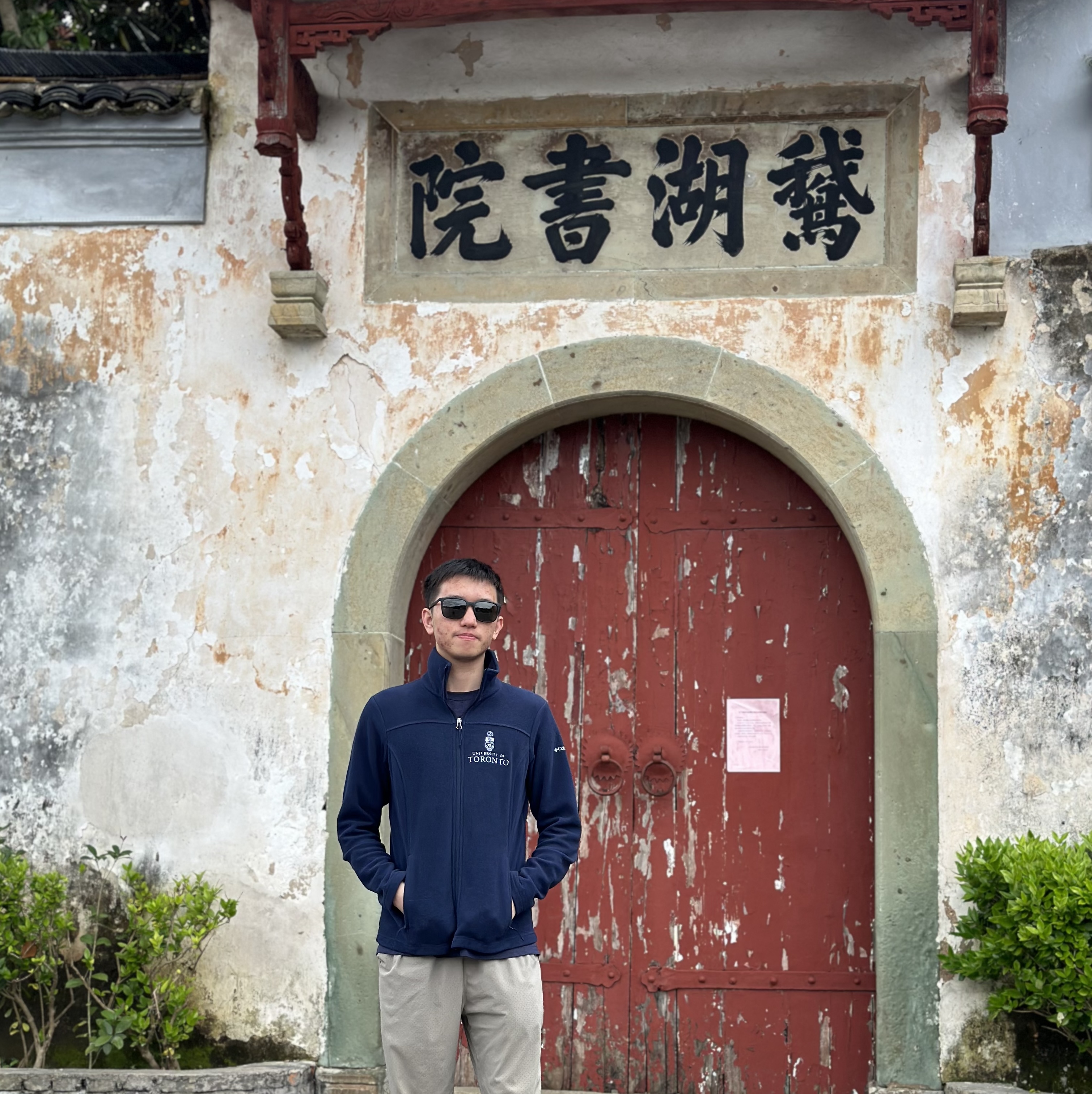 boy in sunglasses wearing blue jacket in front of a chinese-style building